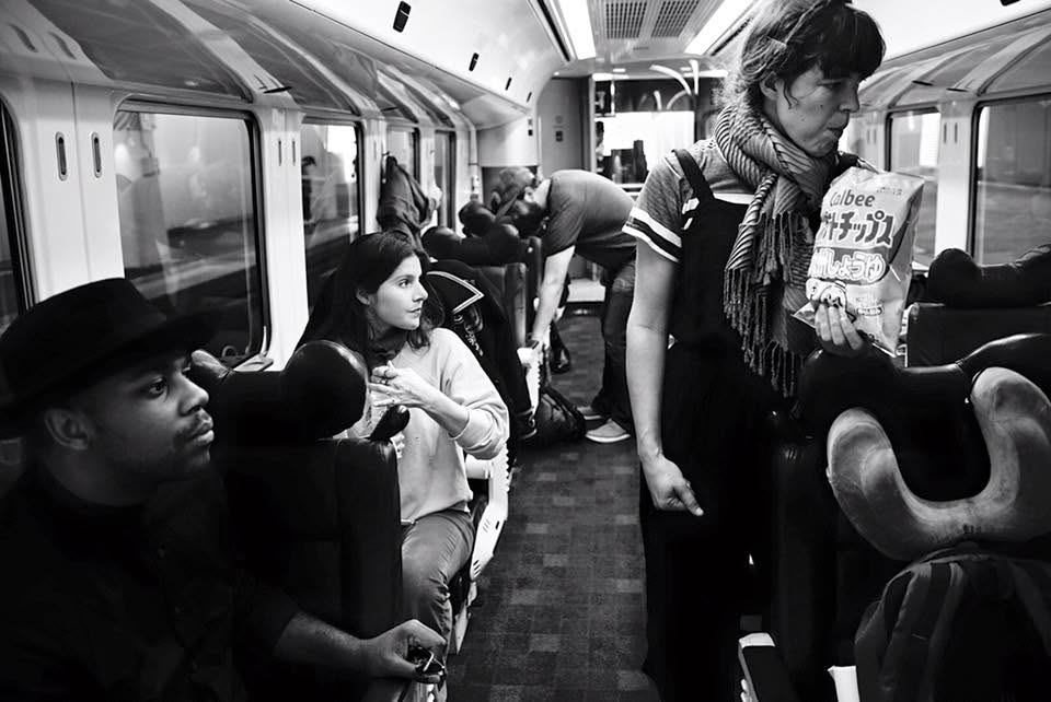 Black-and-white photo inside a train carriage as musicians settle in with their luggage and instruments.