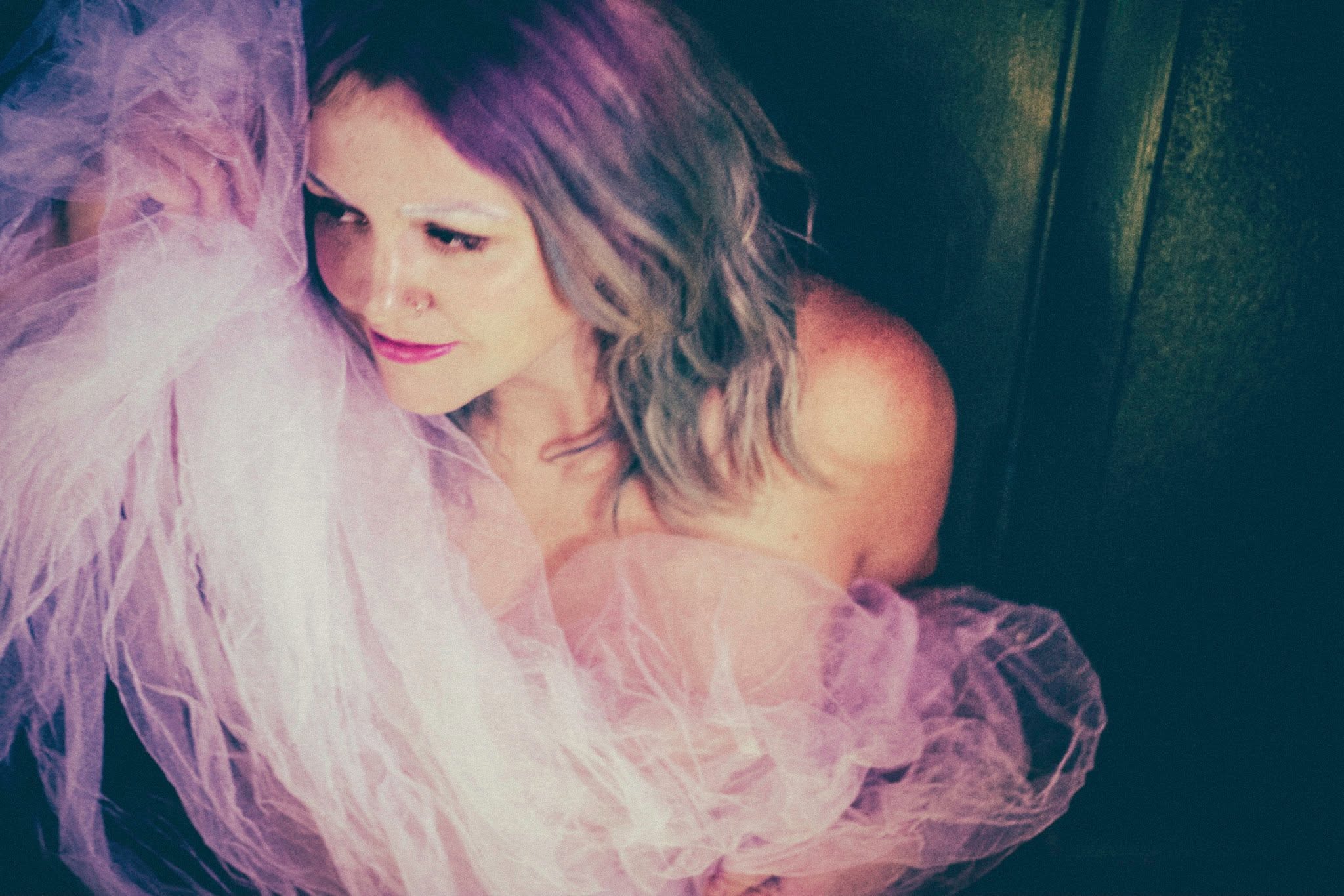 Carrie Fussell wrapped in pink tulle, looking down, in warm low light.